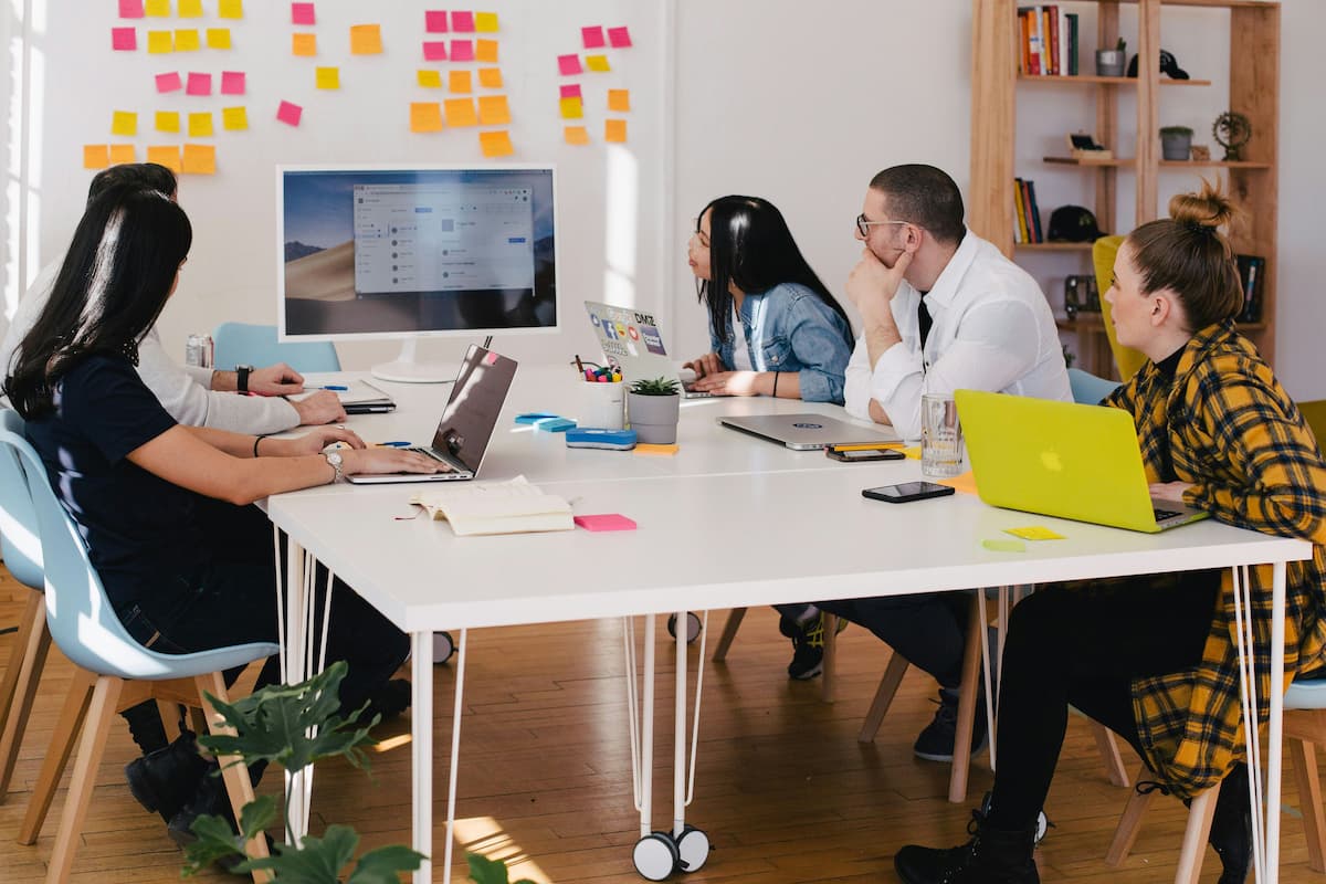 Group of professionals in a meeting, discussing projects with computers and office supplies