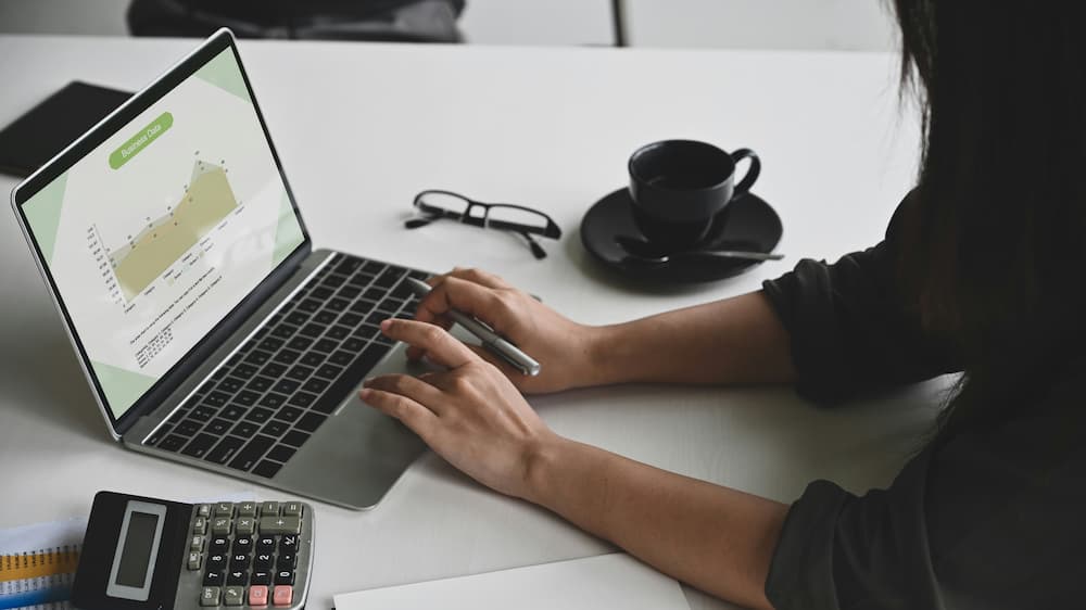 Person analyzing data on a laptop, with charts and financial information on the screen