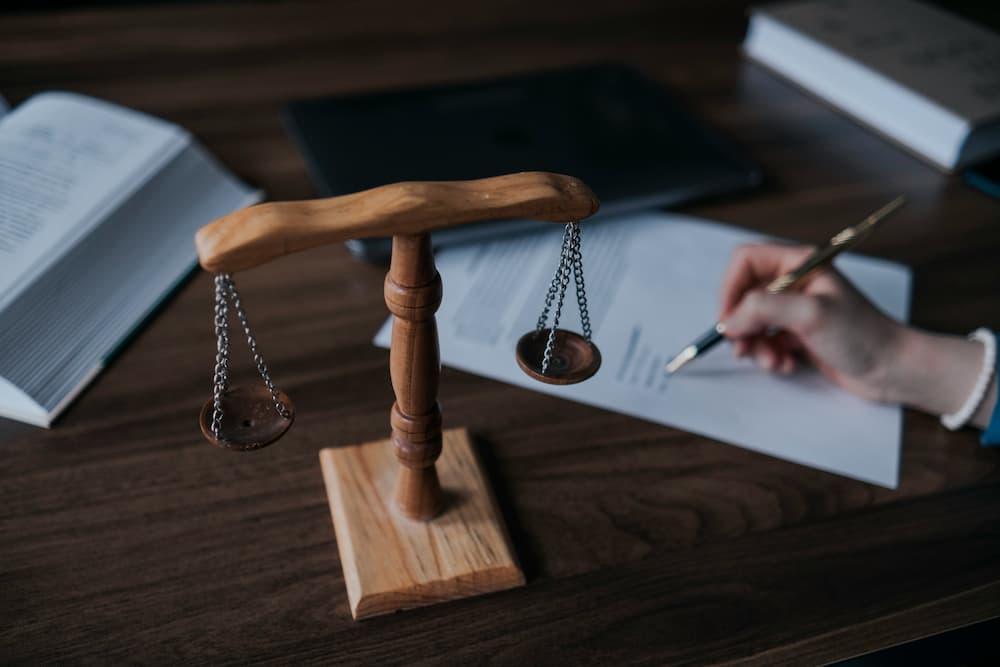 Wooden balance and documents on a table, symbolizing justice and legal activities.