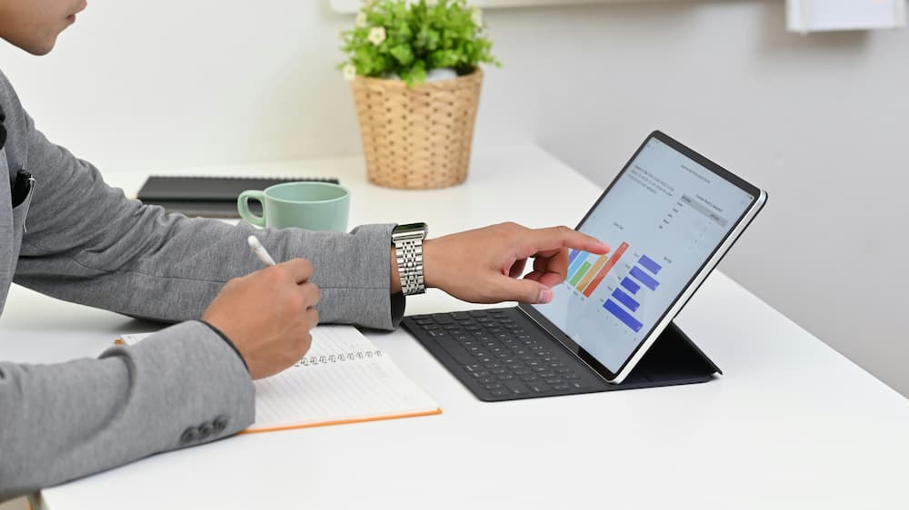 A lawyer analyzing marketing data on a tablet while taking notes.