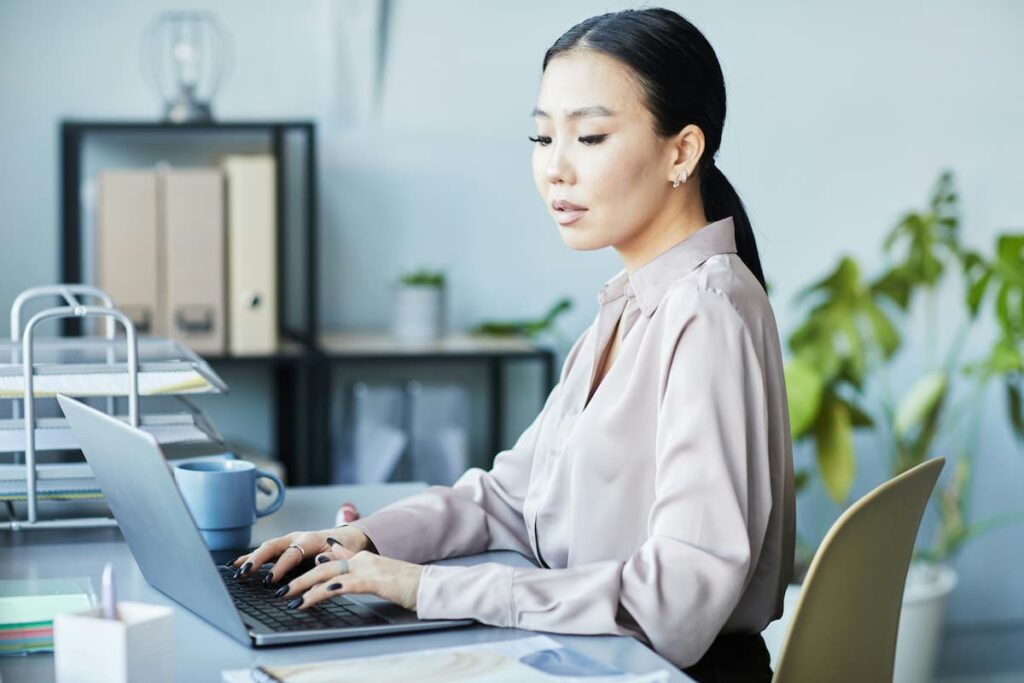 Woman working on a laptop in a modern office, symbolizing accounting tasks that can be automated to save time and reduce errors.