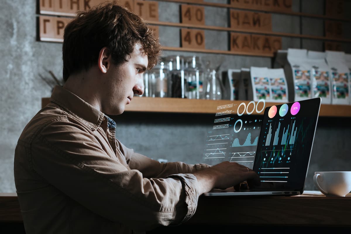 Man analyzing data on a laptop with holographic charts, highlighting limitations of SaaS in AI era for analytics scalability.